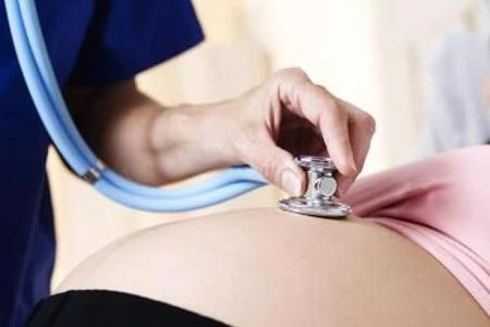 Врач прослушивает живот беременной: лечение запоров при беременности может назначить только специалист.